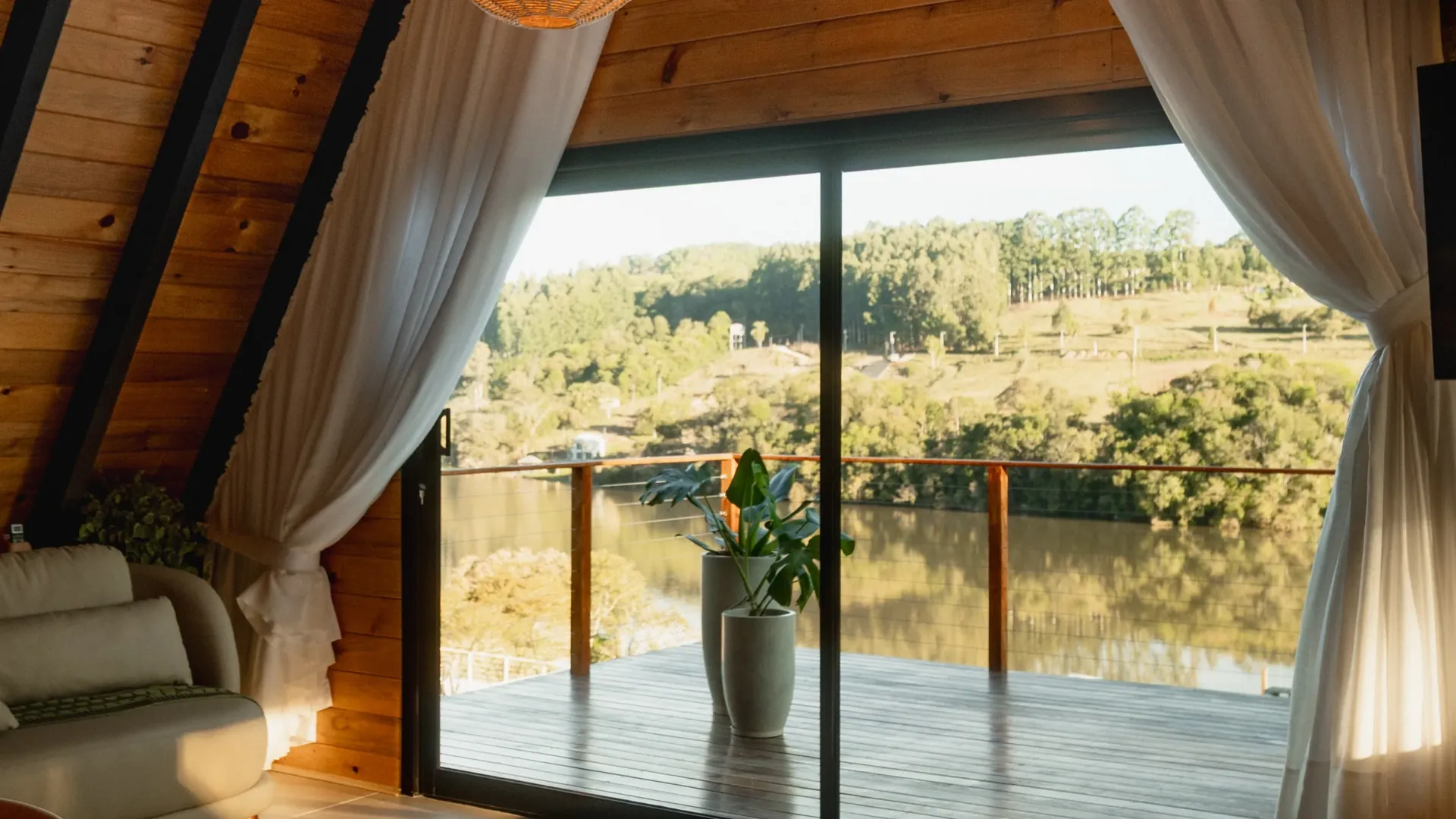 Sala da Cabana Sonhos do Lago com a porta de vidro aberta para a sacada e o lago